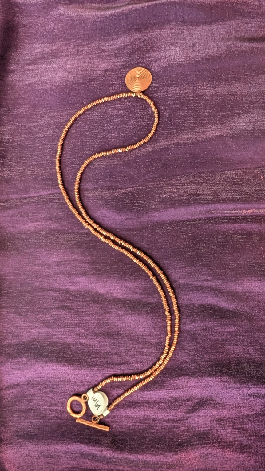 Bronze colored beaded necklace with circular pendant and earrings