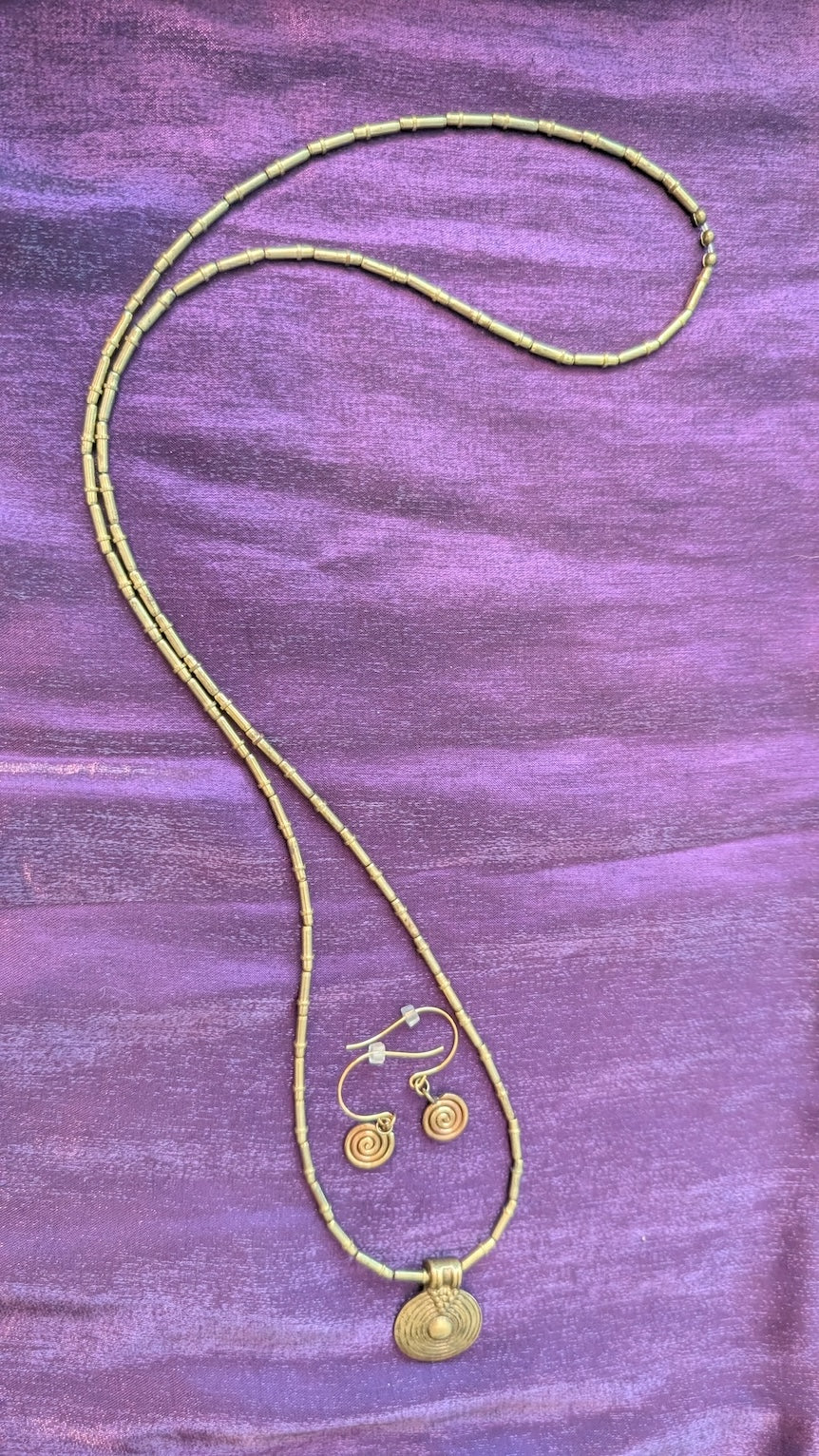 Gold colored beaded necklace with circular pendant and earrings